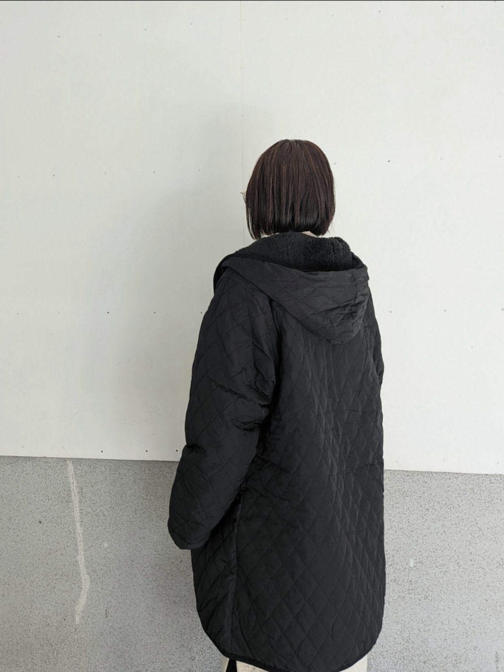 ブラック系のナイロンジャケット、ホワイト系のワンピース、シルバー系のショルダーバッグを着用したレディースの冬コーディネートの4枚目の写真