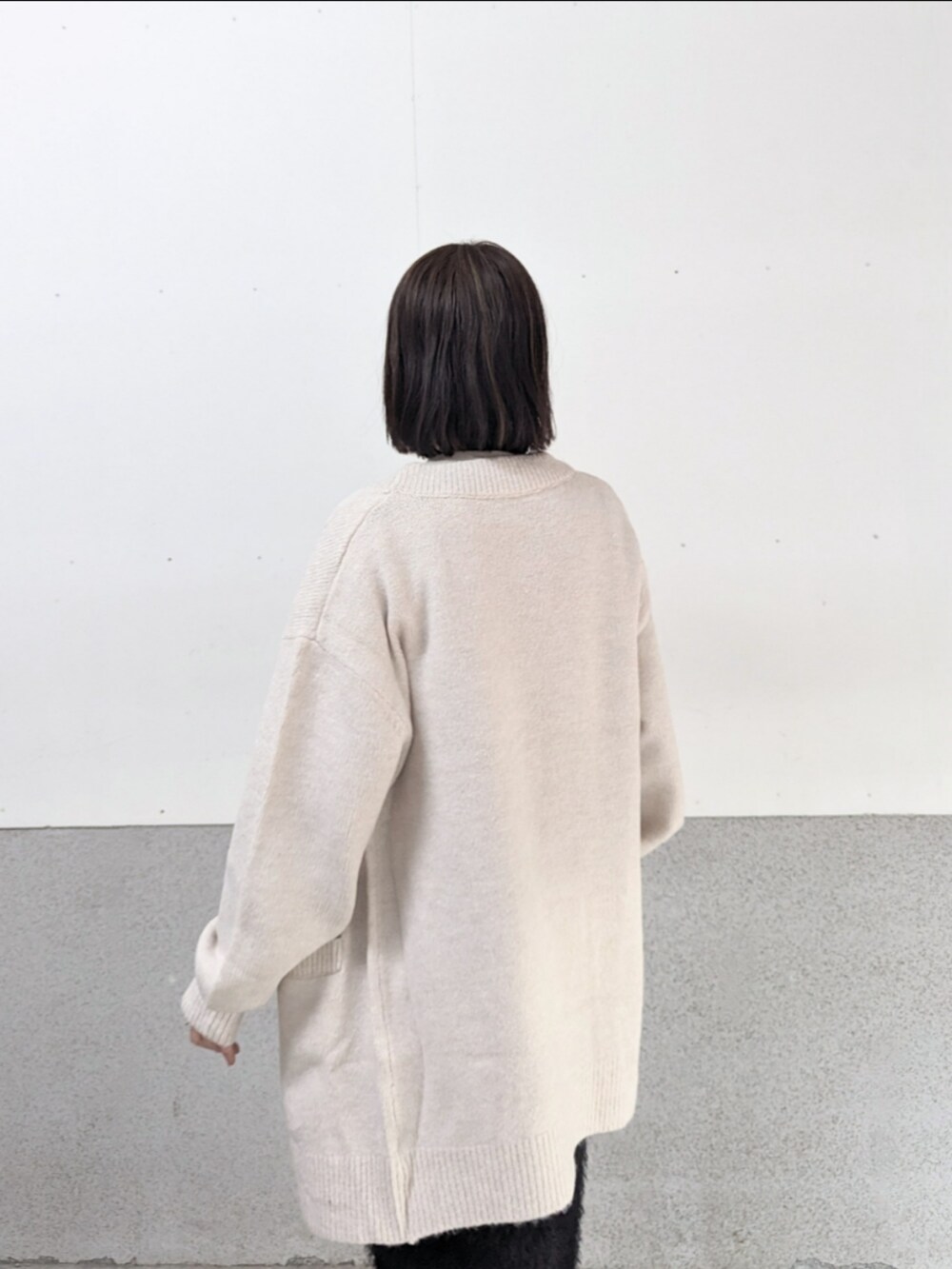 ベージュ系のカーディガン/ボレロ、ホワイト系のニット/セーター、ホワイト系のハンドバッグを着用したレディースの秋コーディネートの3枚目の写真
