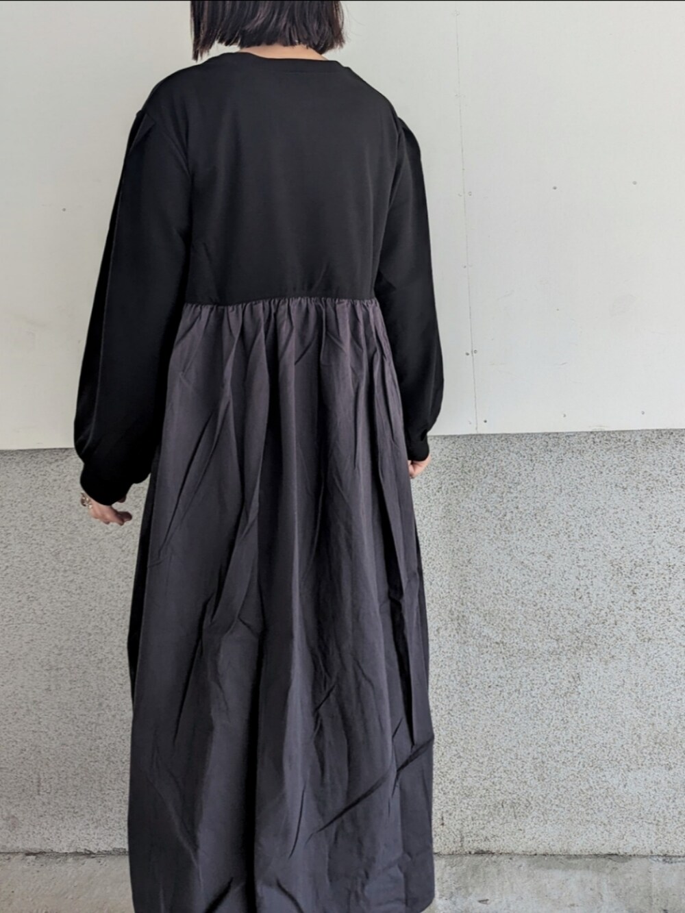 ブラック系のワンピース、ブラック系のブーツ、ホワイト系のハンドバッグを着用したレディースの秋コーディネートの3枚目の写真