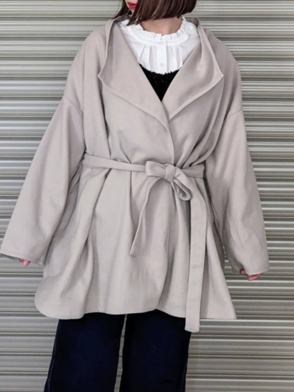 ベージュ系のノーカラーコート、ホワイト系のシャツ/ブラウス、ブラック系のベストを着用したレディースの秋コーディネートの5枚目の写真