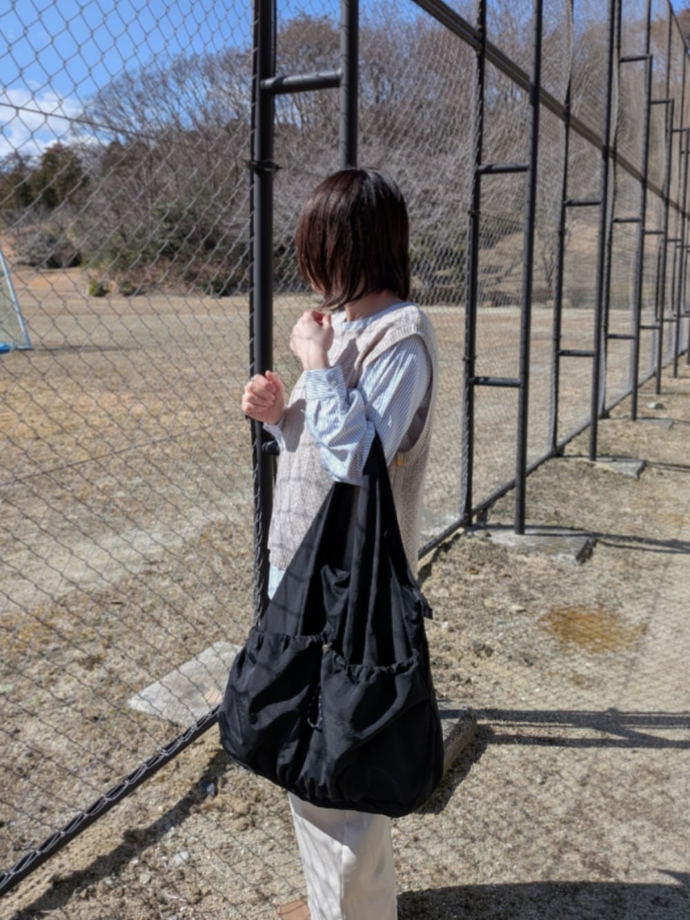 ベージュ系のTシャツ/カットソー、ブラック系のトートバッグ、ベージュ系のローファーを着用したレディースの春コーディネートの4枚目の写真