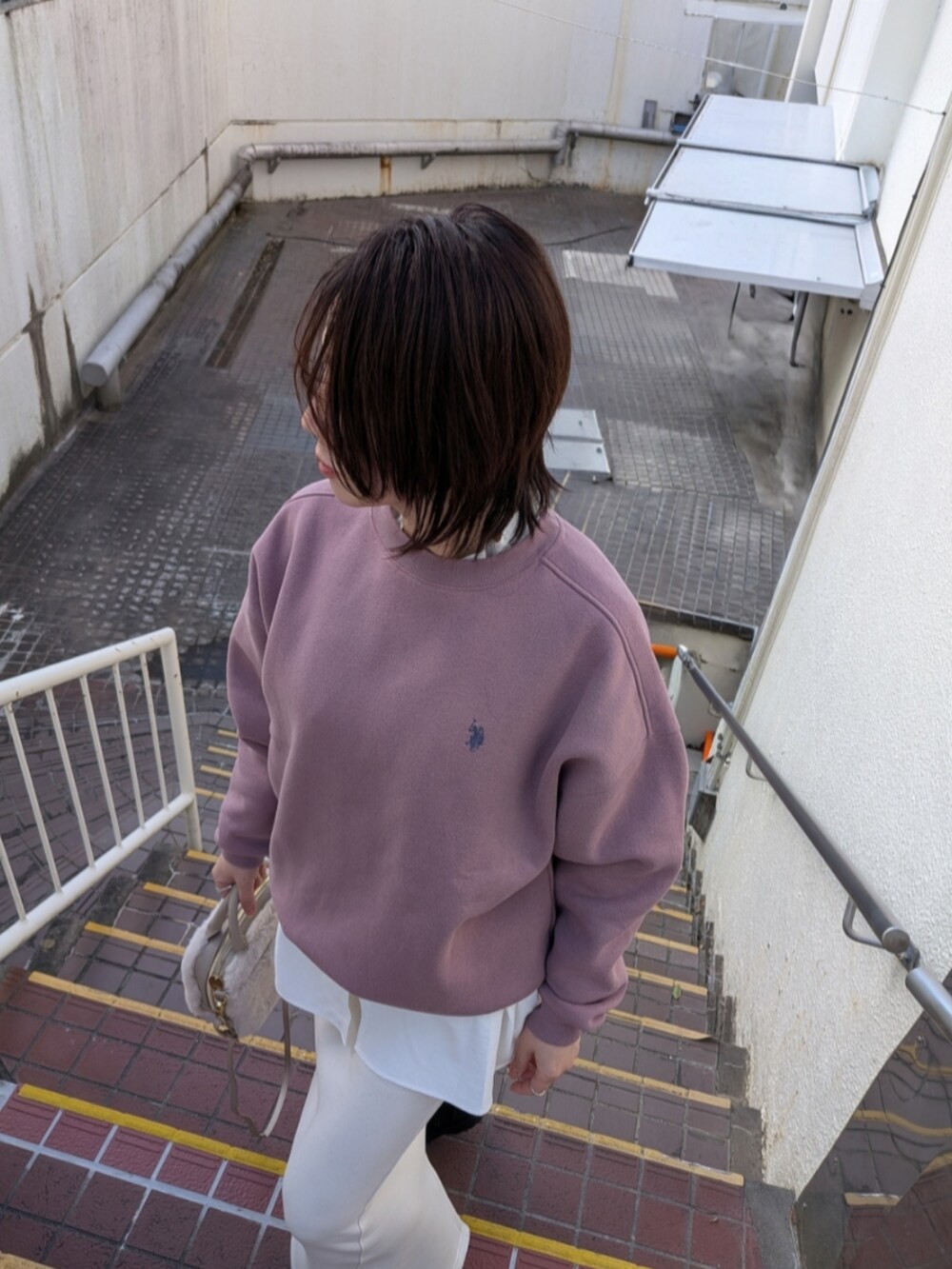 ピンク系のスウェット、ベージュ系のショルダーバッグ、ブラック系のブーツを着用したレディースの冬コーディネートの4枚目の写真