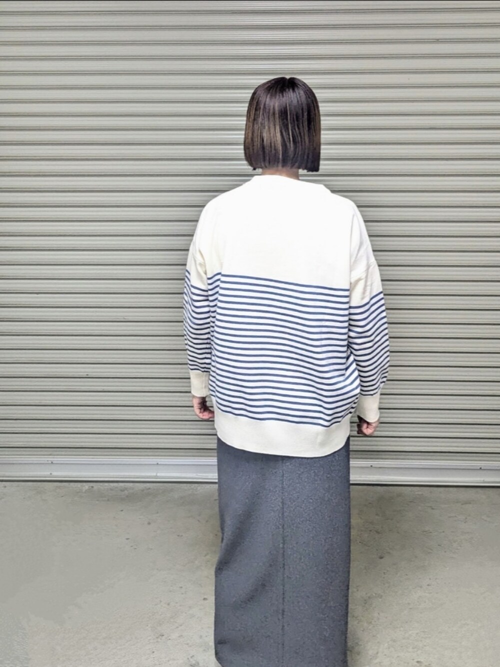 ブルー系のニット/セーター、ホワイト系のダウンジャケット/コート、ベージュ系のブーツを着用したレディースの秋コーディネートの4枚目の写真