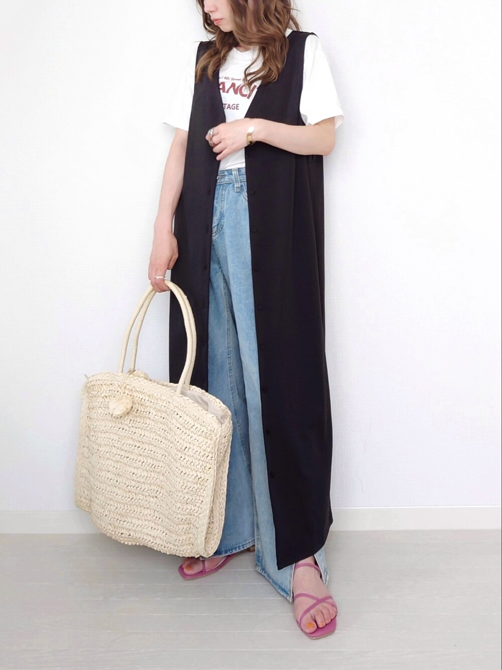 ブルー系のデニムパンツ、イエロー系のサンダル、ブラック系のジャンパースカートを着用したレディースの夏コーディネートの2枚目の写真