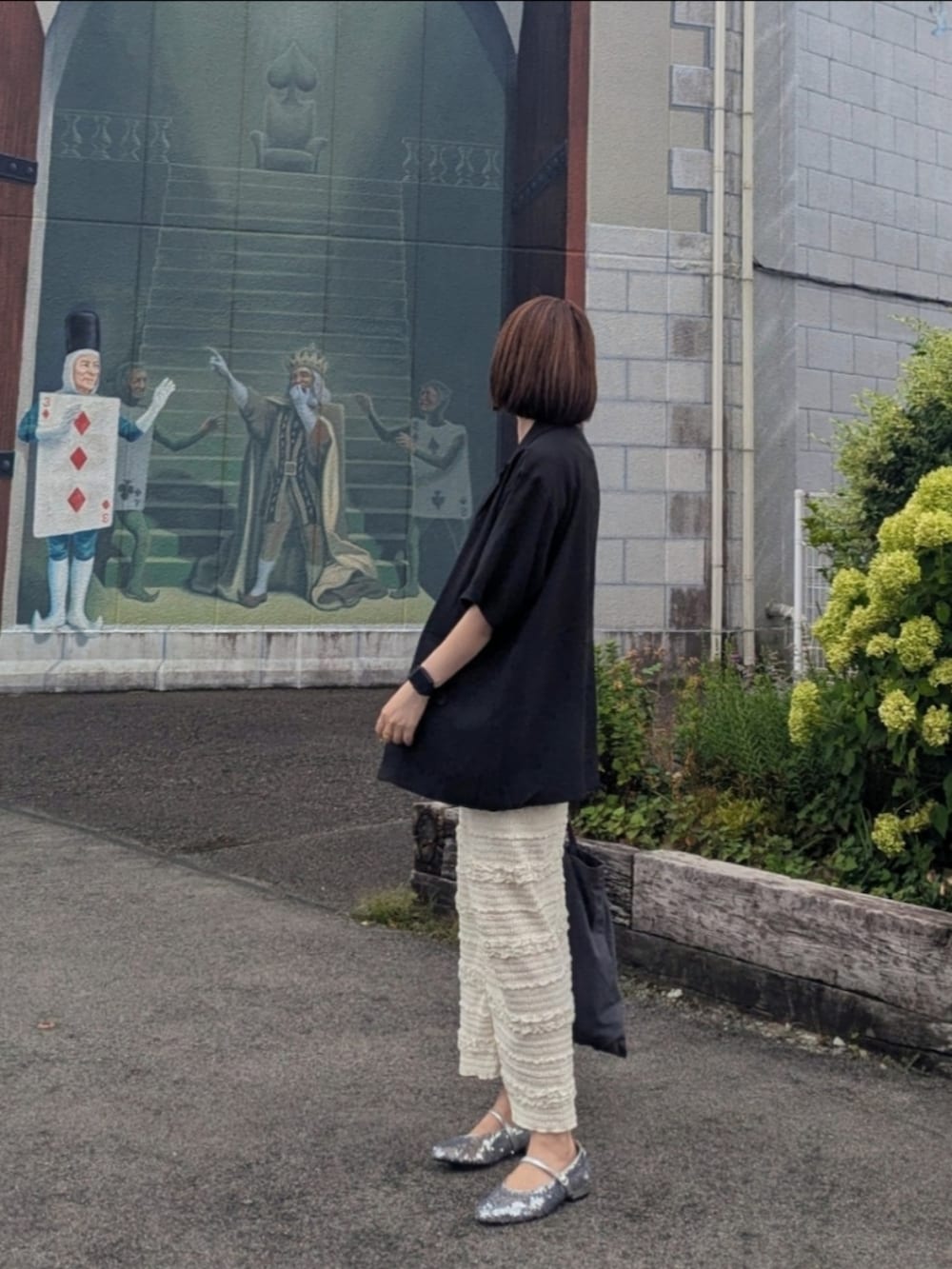 ブラック系のテーラードジャケット、ホワイト系のスカート、ブラック系のキャミソールを着用したレディースの夏コーディネートの2枚目の写真