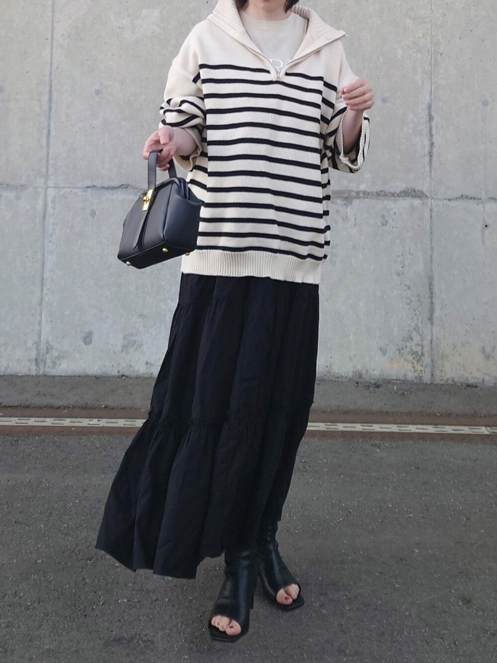 ホワイト系のニット/セーター、ブラック系のスカート、ブラック系のブーツを着用したレディースの春コーディネートの2枚目の写真