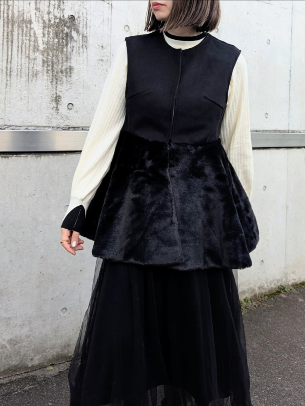 ブラック系のベスト、ホワイト系のニット/セーター、ベージュ系のショルダーバッグを着用したレディースの秋コーディネートの2枚目の写真