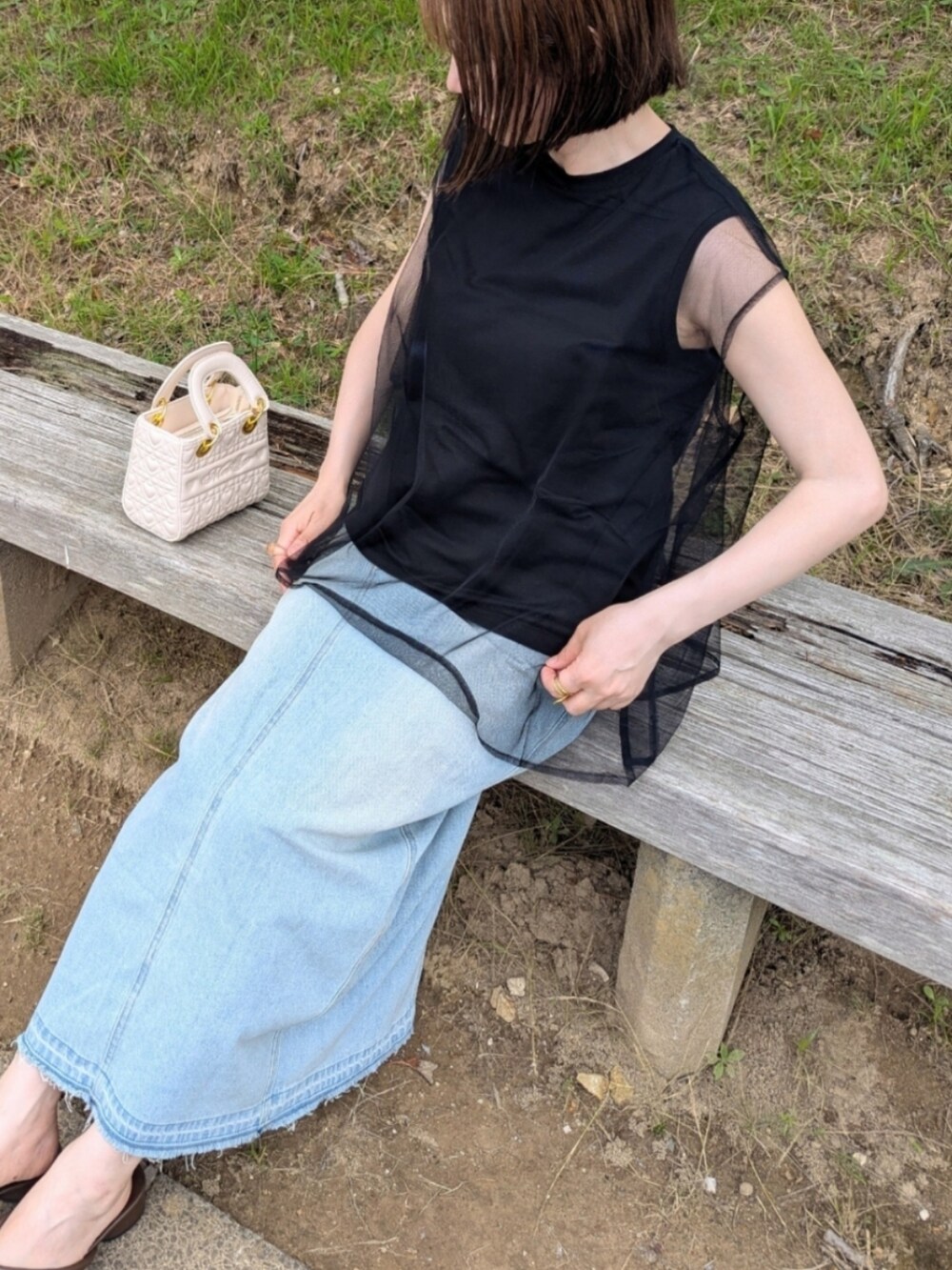 ブラック系のTシャツ/カットソー、ブルー系のスカート、ホワイト系のハンドバッグを着用したレディースの夏コーディネートの2枚目の写真