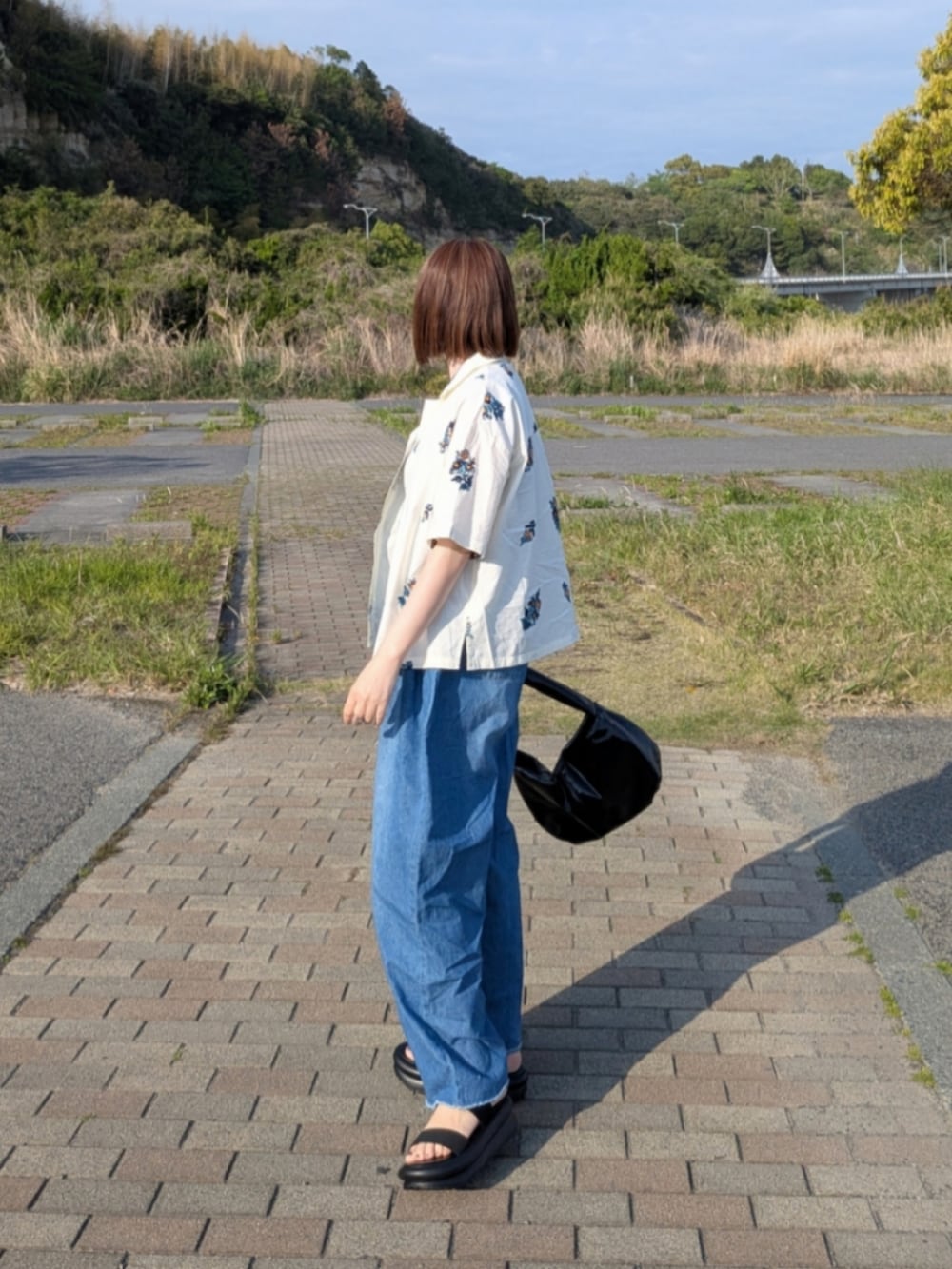 イエロー系のシャツ/ブラウス、ブルー系のデニムパンツ、ブラック系のタンクトップを着用したレディースの春コーディネートの4枚目の写真