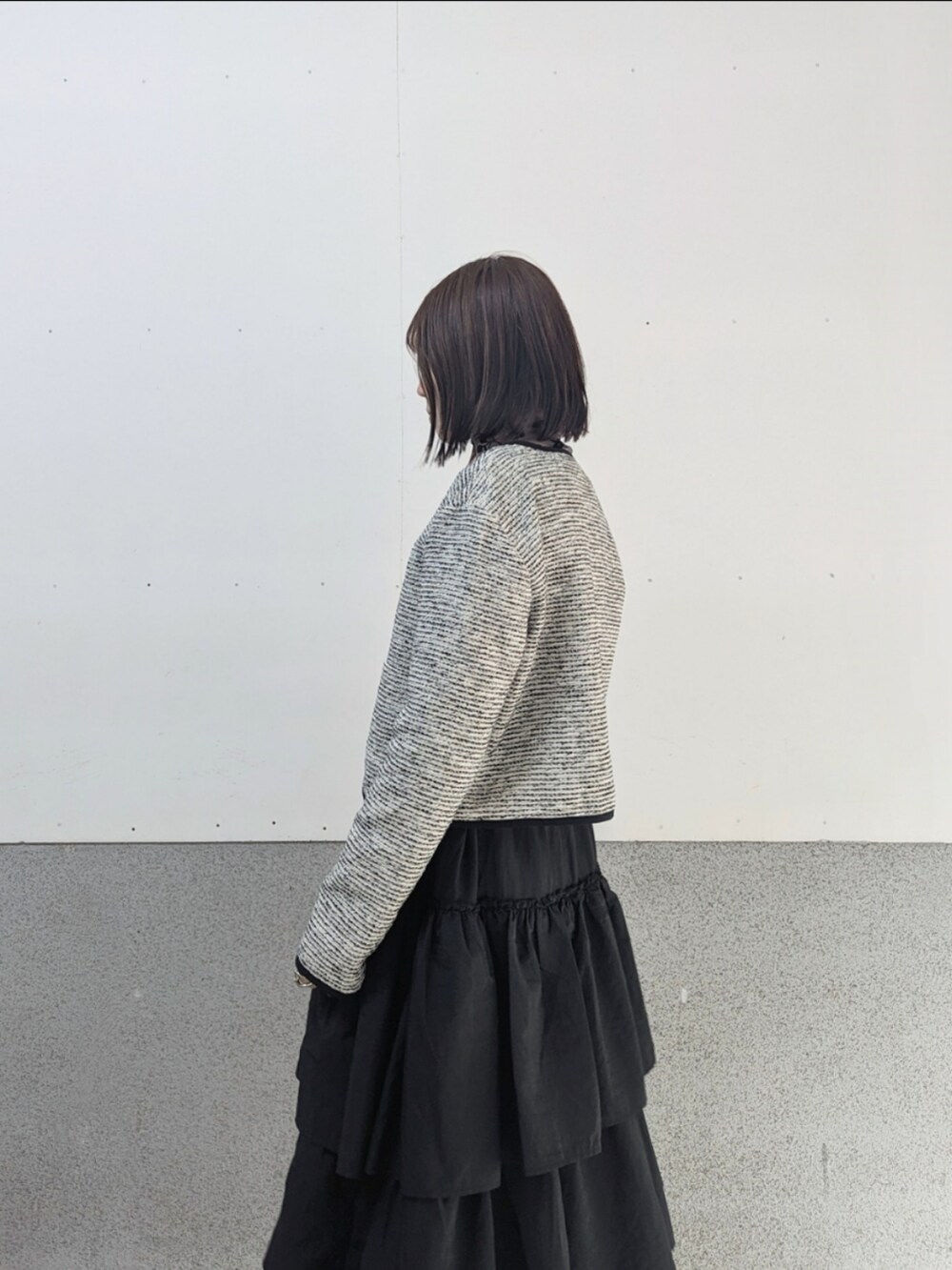 ホワイト系のノーカラージャケット、ブラック系のスカート、ブラウン系のその他トップスを着用したレディースの冬コーディネートの2枚目の写真