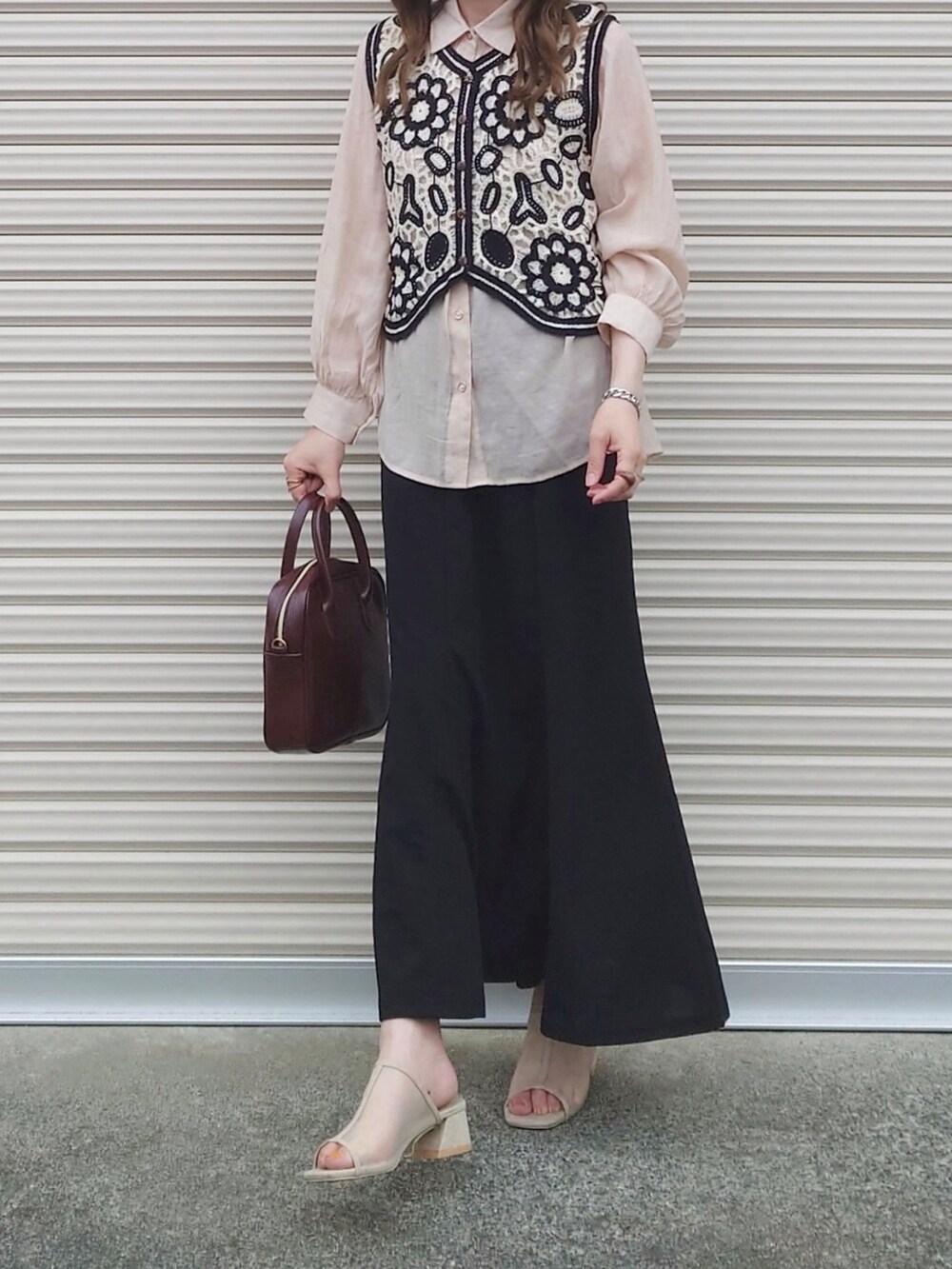 ブラック系のスカート、レッド系のハンドバッグ、ベージュ系のシャツ/ブラウスを着用したレディースの夏コーディネートの2枚目の写真