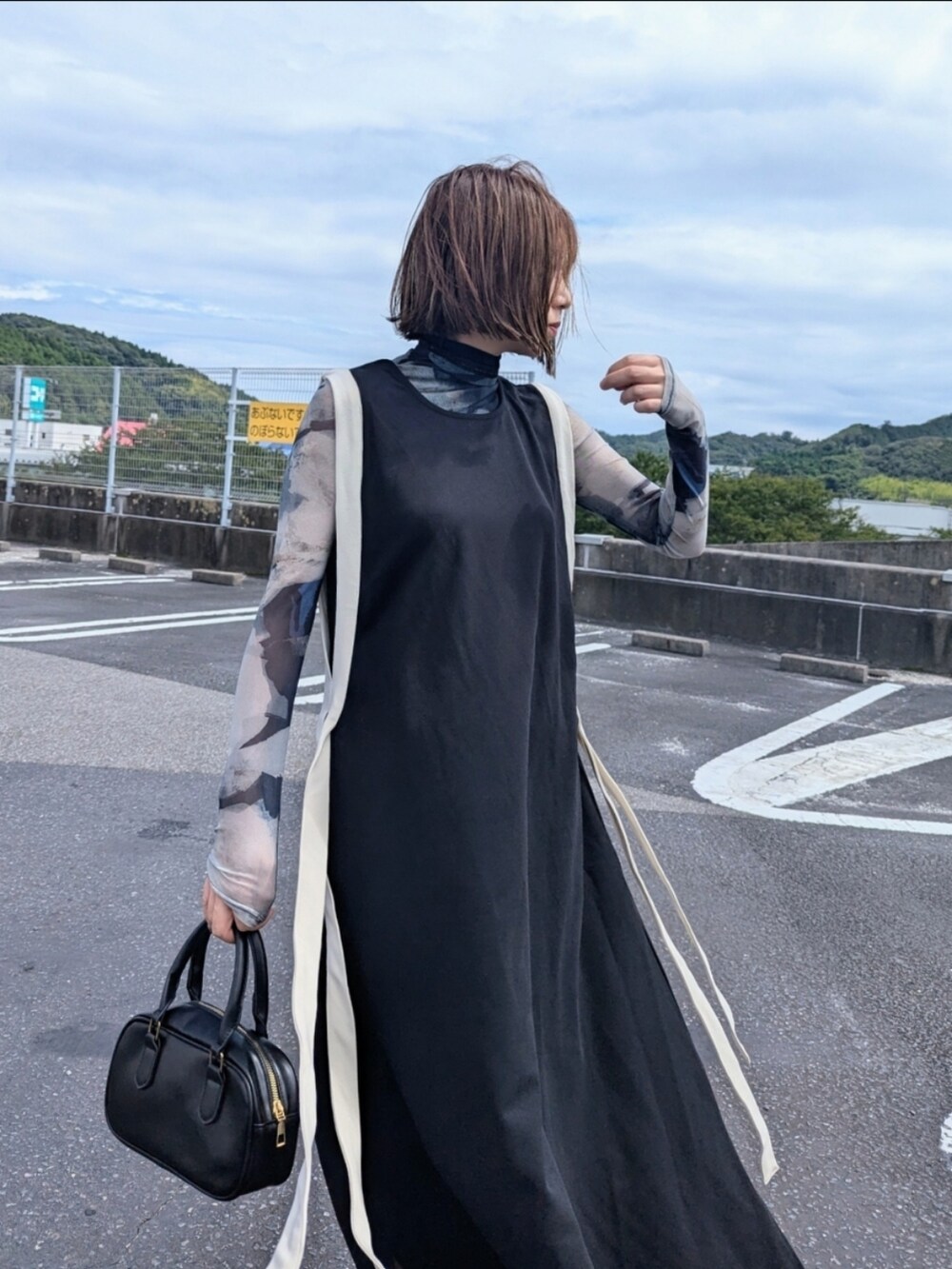 ブラック系のワンピース、グリーン系のその他トップス、ブラック系のブーツを着用したレディースの秋コーディネートの2枚目の写真