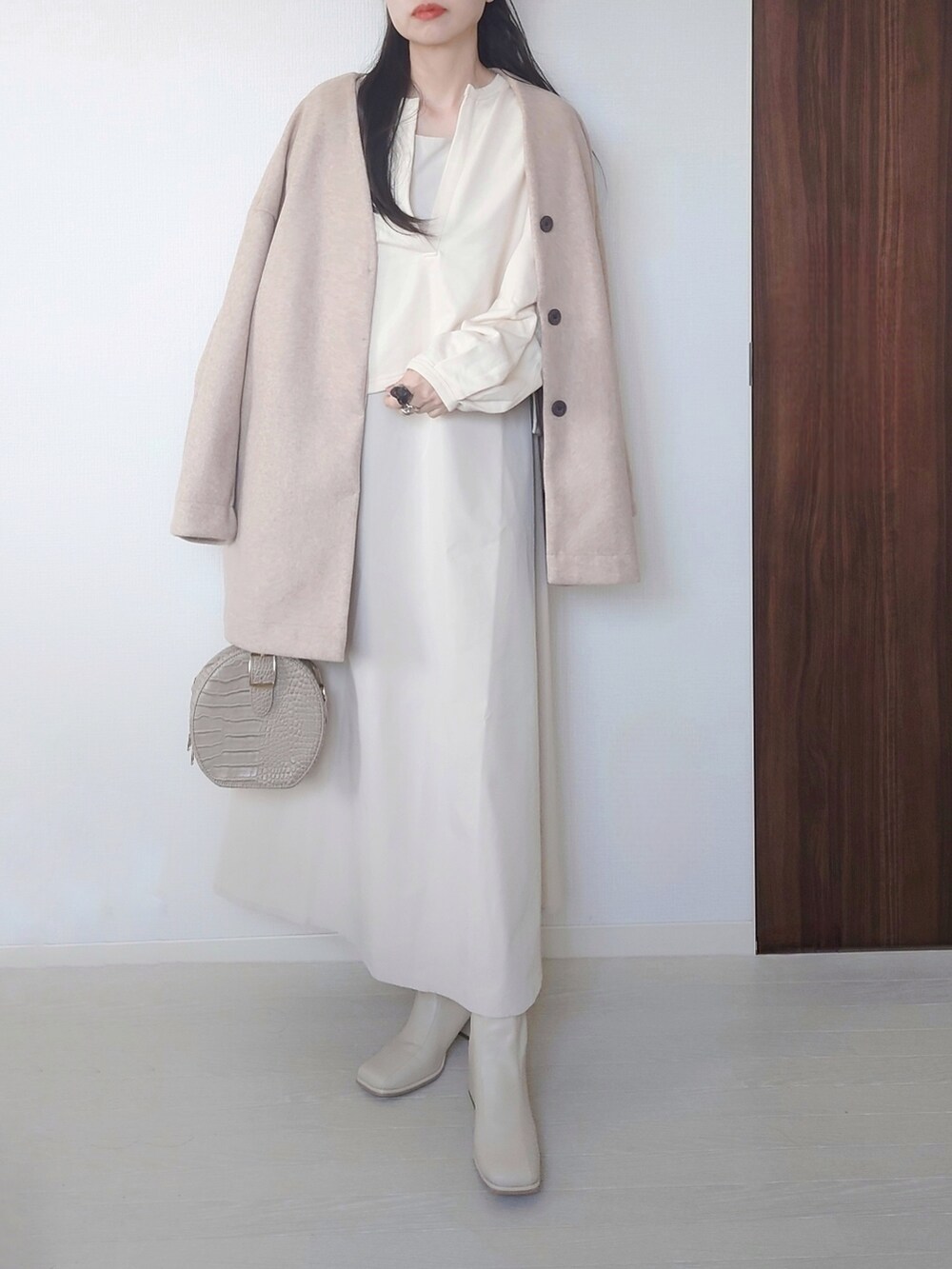ホワイト系のその他アウター、ベージュ系のノーカラーコート、ホワイト系のブーツを着用したレディースの冬コーディネートの2枚目の写真