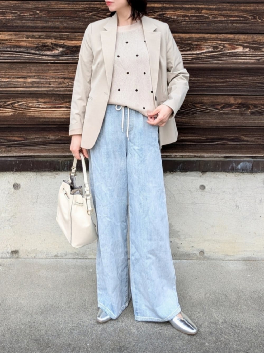 ベージュ系のニット/セーター、ブルー系のデニムパンツ、ホワイト系のショルダーバッグを着用したレディースの春コーディネートの5枚目の写真