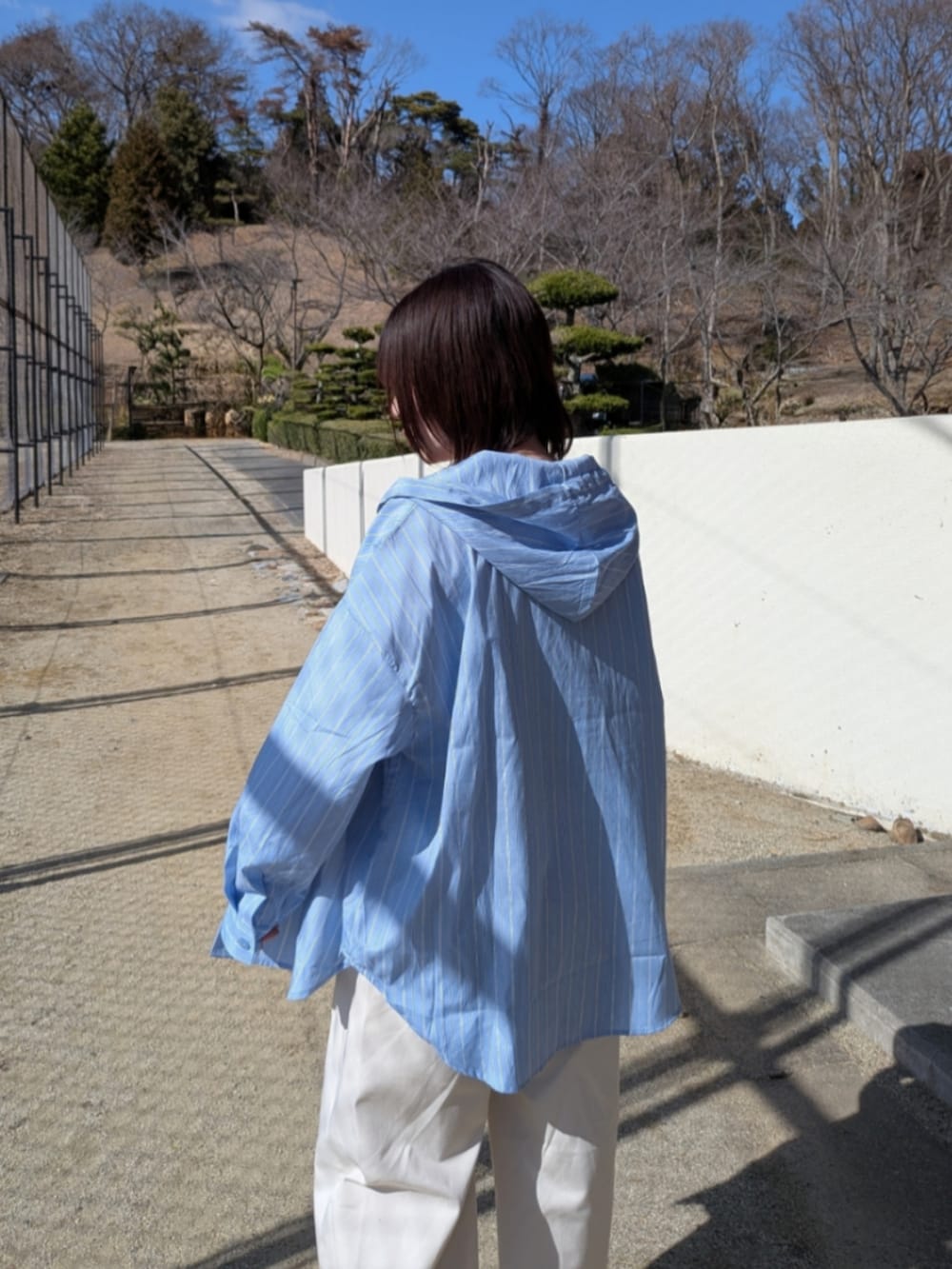 ブルー系のシャツ/ブラウス、ブラック系のショルダーバッグ、ベージュ系のローファーを着用したレディースの春コーディネートの4枚目の写真