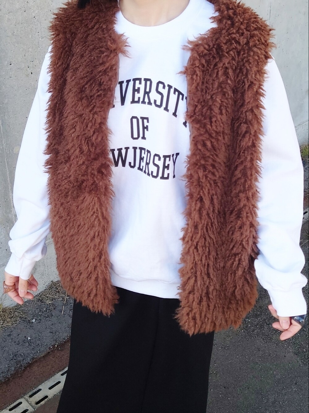 ホワイト系のスウェット、ブラウン系のベスト、ブラック系のボディバッグ/ウエストポーチを着用したレディースの冬コーディネートの2枚目の写真