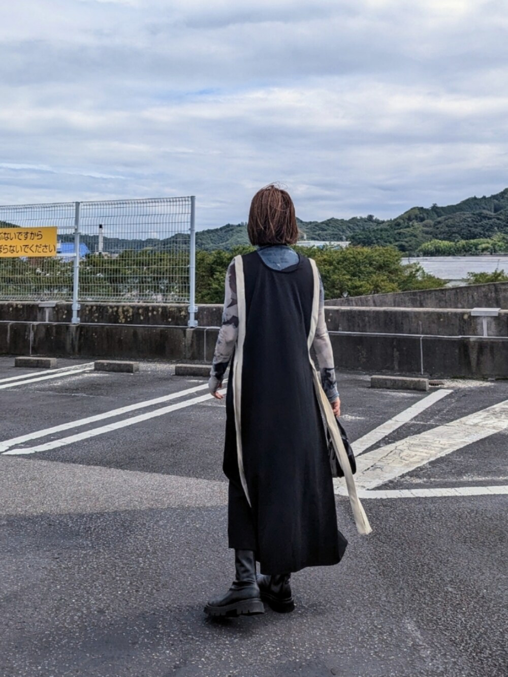 ブラック系のワンピース、グリーン系のその他トップス、ブラック系のブーツを着用したレディースの秋コーディネートの3枚目の写真