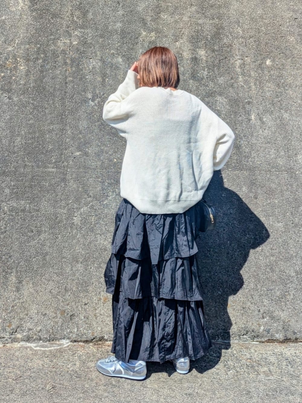 ホワイト系のニット/セーター、ブラック系のスカート、シルバー系のスニーカーを着用したレディースの春コーディネートの2枚目の写真