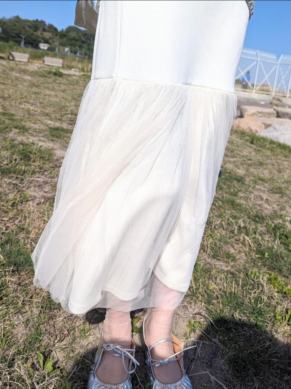 ホワイト系のスカート、グレー系のニット/セーター、シルバー系のショルダーバッグを着用したレディースの春コーディネートの3枚目の写真