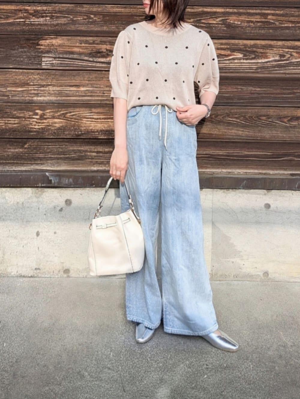 ベージュ系のニット/セーター、ブルー系のデニムパンツ、ホワイト系のショルダーバッグを着用したレディースの春コーディネートの2枚目の写真