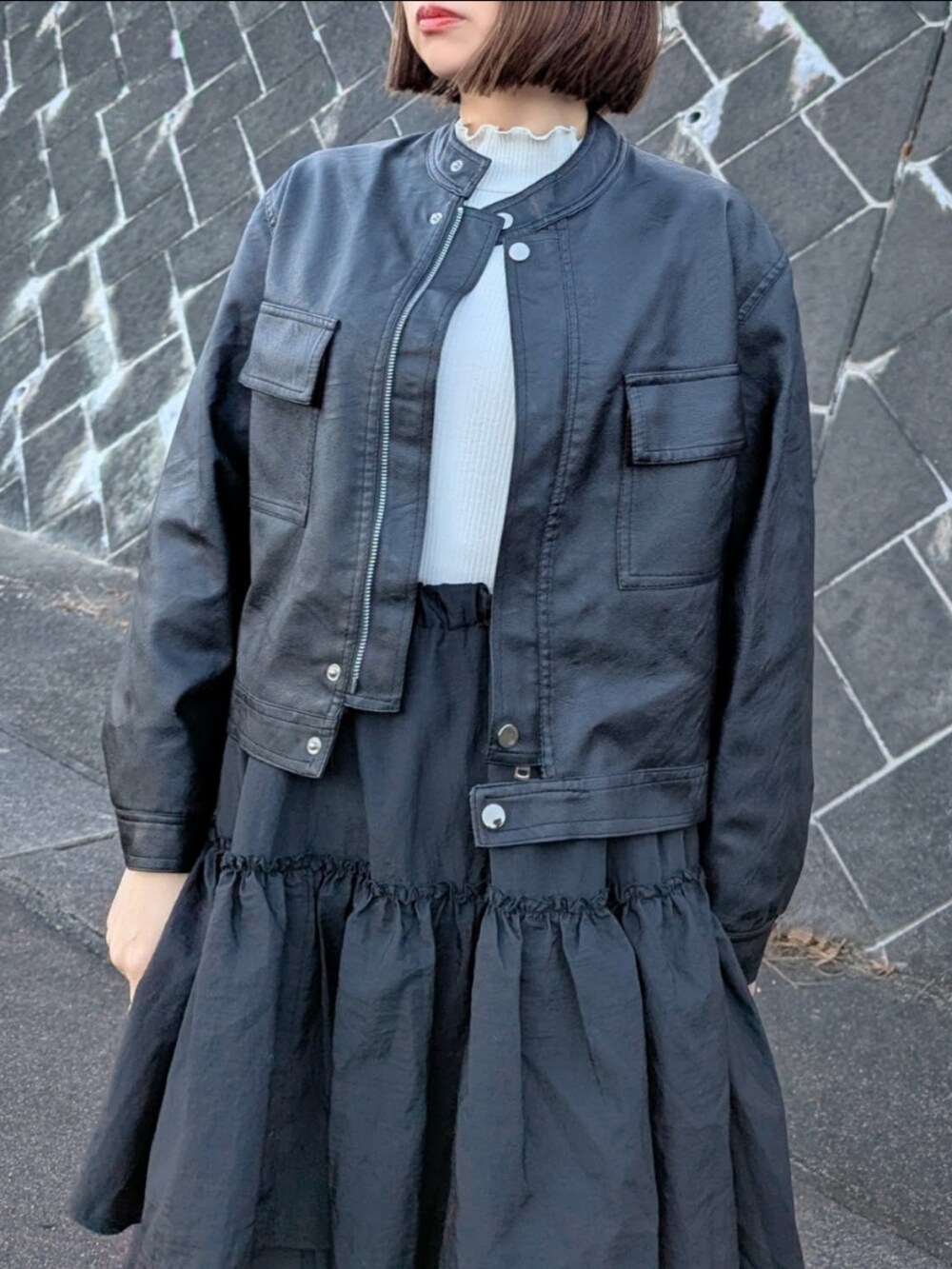 ブラック系のブルゾン、ブラック系のスカート、ホワイト系のTシャツ/カットソーを着用したレディースの冬コーディネートの4枚目の写真