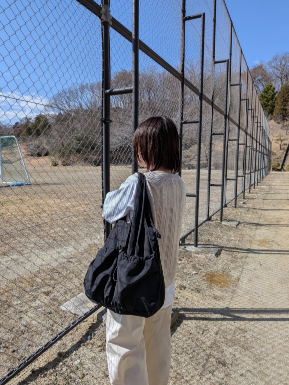 ベージュ系のTシャツ/カットソー、ブラック系のトートバッグ、ベージュ系のローファーを着用したレディースの春コーディネートの5枚目の写真