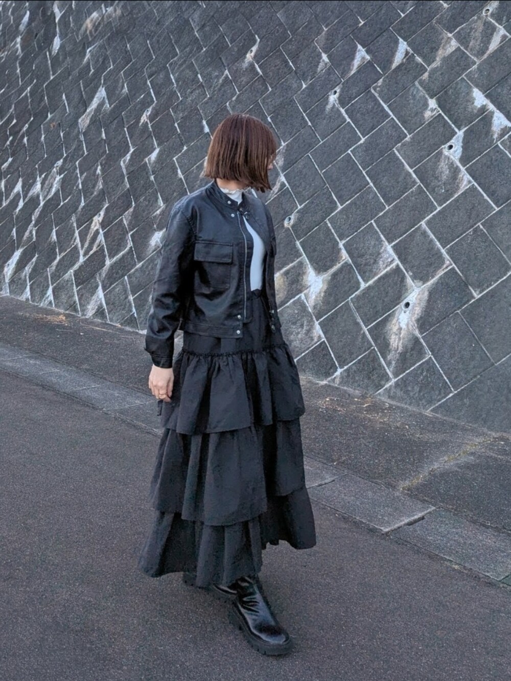 ブラック系のブルゾン、ブラック系のスカート、ホワイト系のTシャツ/カットソーを着用したレディースの冬コーディネートの2枚目の写真