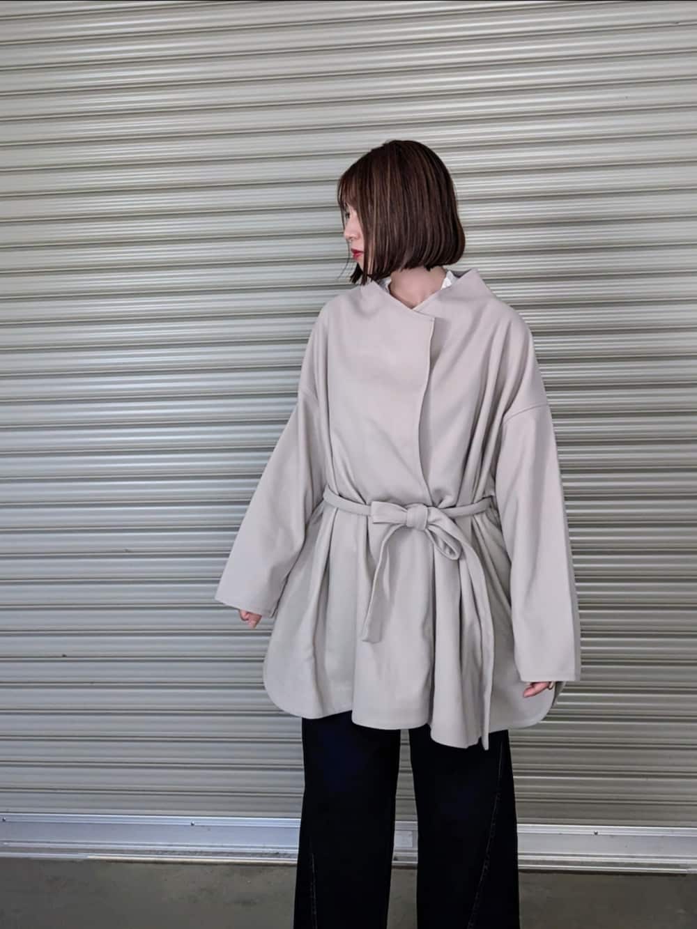 ベージュ系のノーカラーコート、ホワイト系のシャツ/ブラウス、ブラック系のベストを着用したレディースの秋コーディネートの3枚目の写真