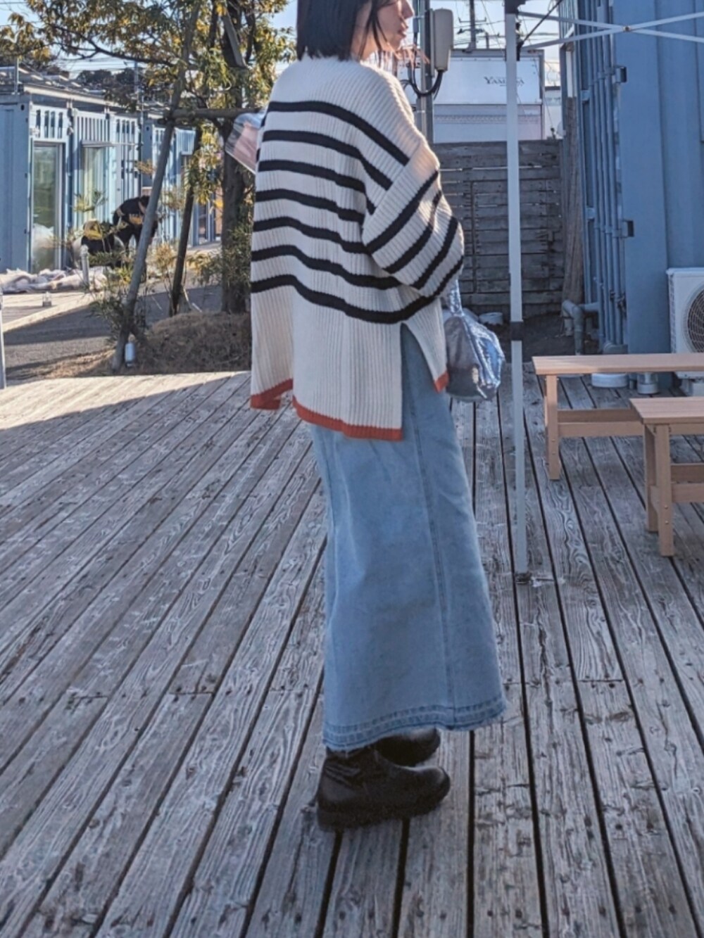 ブルー系のスカート、ホワイト系のニット/セーター、シルバー系のバッグを着用したレディースの春コーディネートの2枚目の写真