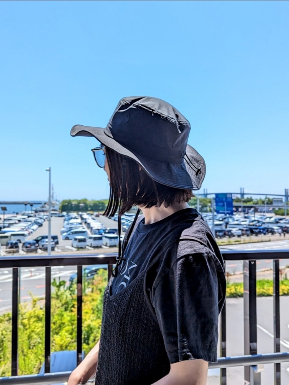 ブラック系のTシャツ/カットソー、ブラック系のショルダーバッグ、ブルー系のデニムパンツを着用したレディースの夏コーディネートの2枚目の写真