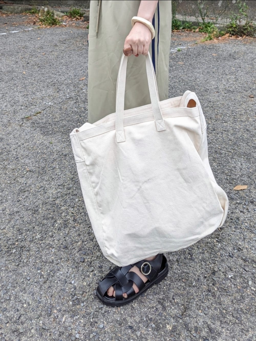 ブラック系のTシャツ/カットソー、ブルー系のスカート、ベージュ系のショルダーバッグを着用したレディースの春コーディネートの4枚目の写真