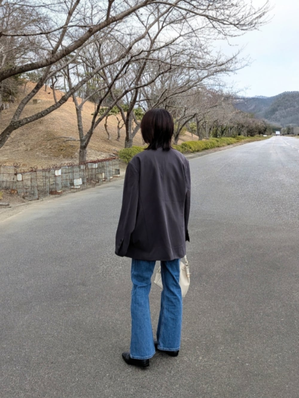 グレー系のテーラードジャケット、ブラック系のキャミソール、ホワイト系のショルダーバッグを着用したレディースの春コーディネートの2枚目の写真