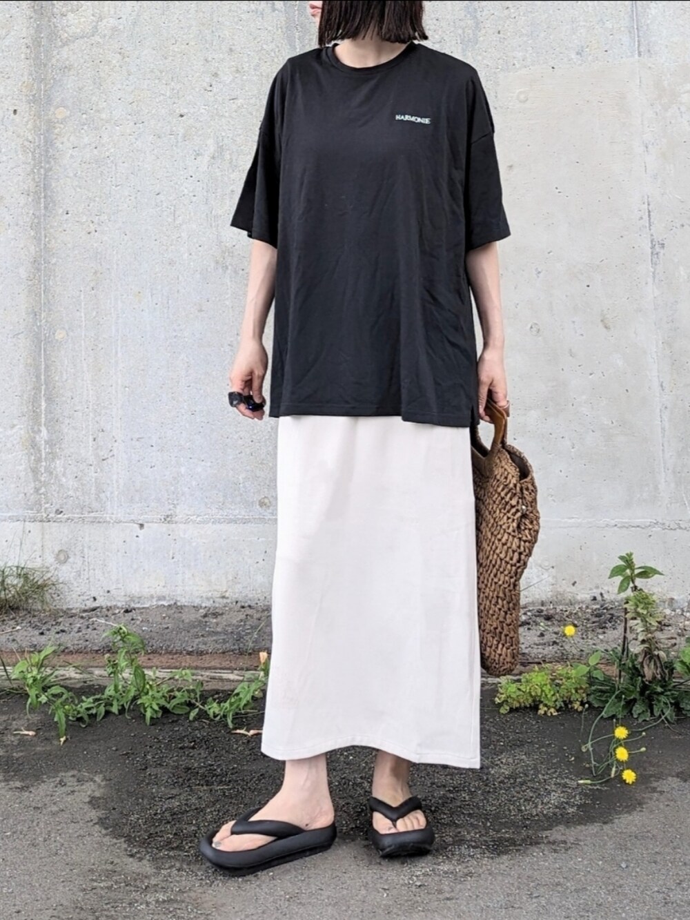 ブラック系のTシャツ/カットソー、ホワイト系のスカート、ブラウン系のかごバッグを着用したレディースの夏コーディネートの3枚目の写真
