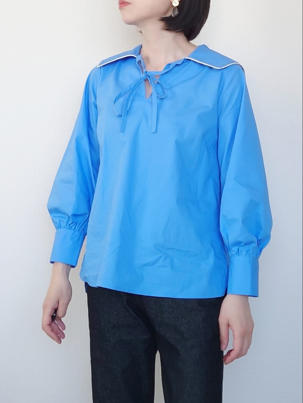 ブルー系のシャツ/ブラウス、ブラック系のジャンパースカート、ホワイト系のブーツを着用したレディースの春コーディネートの3枚目の写真