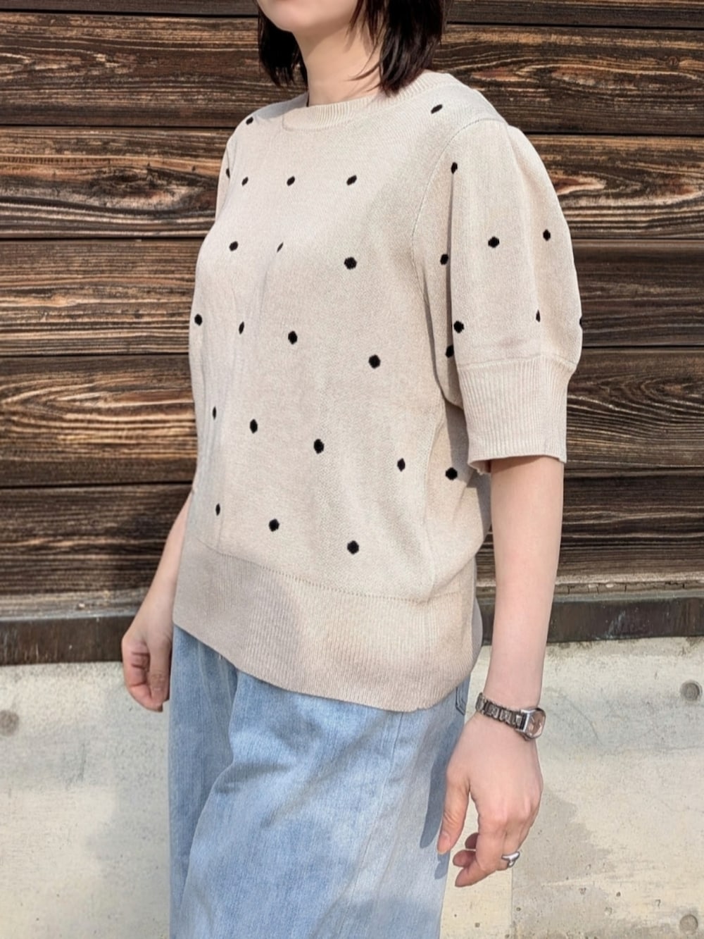 ベージュ系のニット/セーター、ブルー系のデニムパンツ、ホワイト系のショルダーバッグを着用したレディースの春コーディネートの4枚目の写真