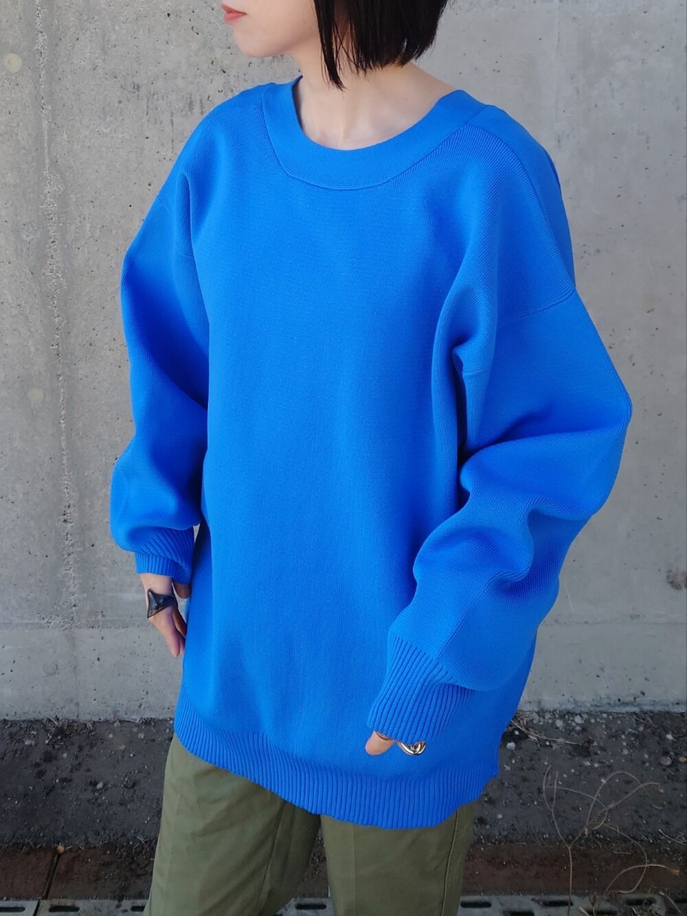 ブルー系のカーディガン/ボレロ、グリーン系のチノパンツ、ブラック系のバックパック/リュックを着用したレディースの春コーディネートの2枚目の写真