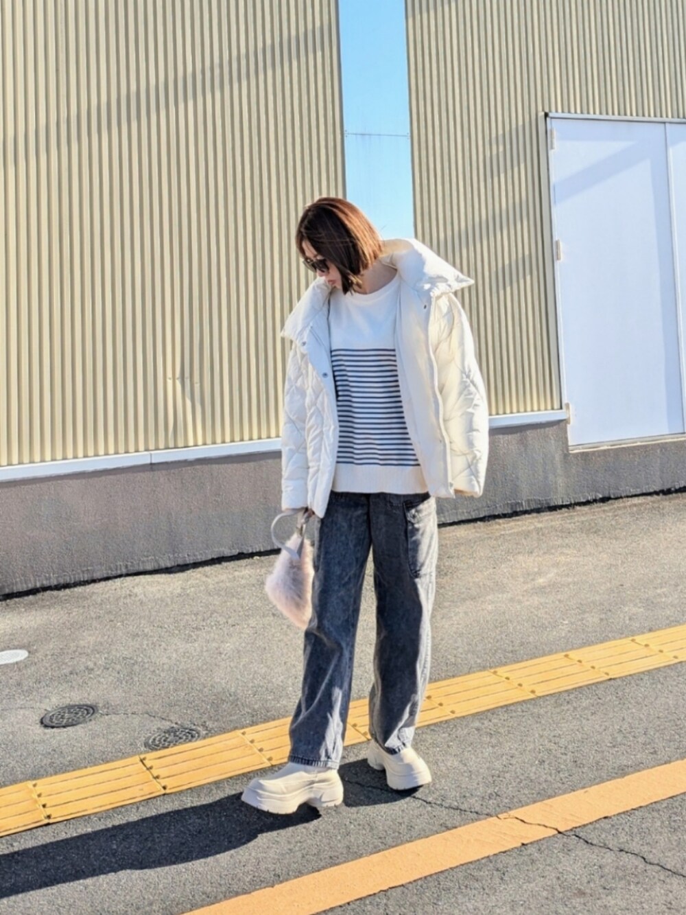 ブルー系のニット/セーター、ホワイト系のダウンジャケット/コート、ベージュ系のブーツを着用したレディースの秋コーディネートの2枚目の写真