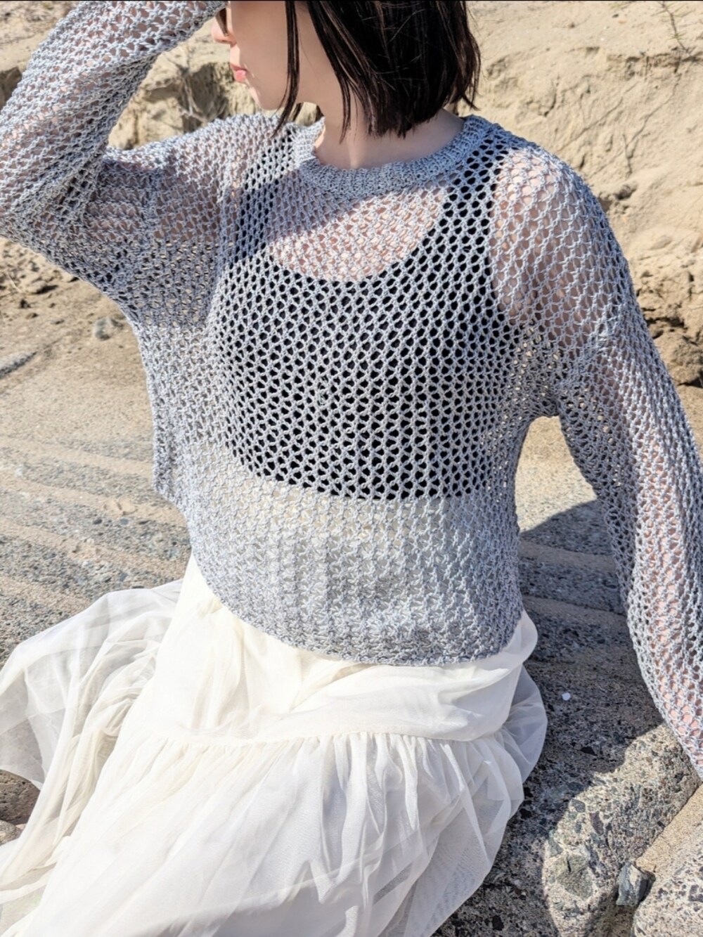 ホワイト系のスカート、グレー系のニット/セーター、シルバー系のショルダーバッグを着用したレディースの春コーディネートの4枚目の写真