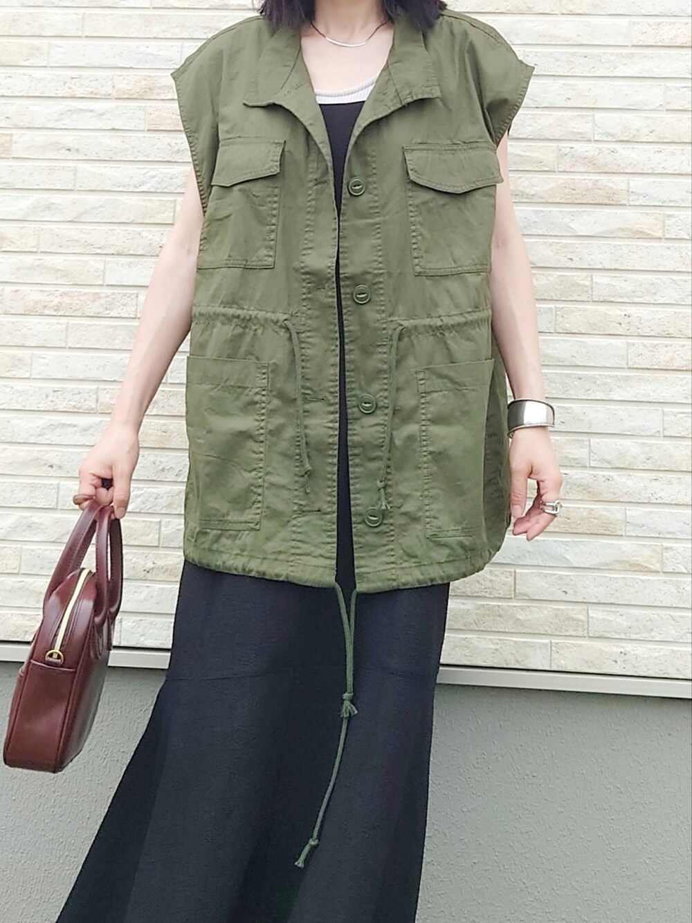 ブラック系のワンピース、グリーン系のベスト、ブラック系のサンダルを着用したレディースの夏コーディネートの3枚目の写真