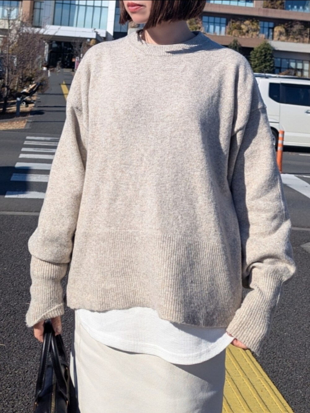 ベージュ系のニット/セーター、ホワイト系のTシャツ/カットソー、ホワイト系のスカートを着用したレディースの冬コーディネートの2枚目の写真
