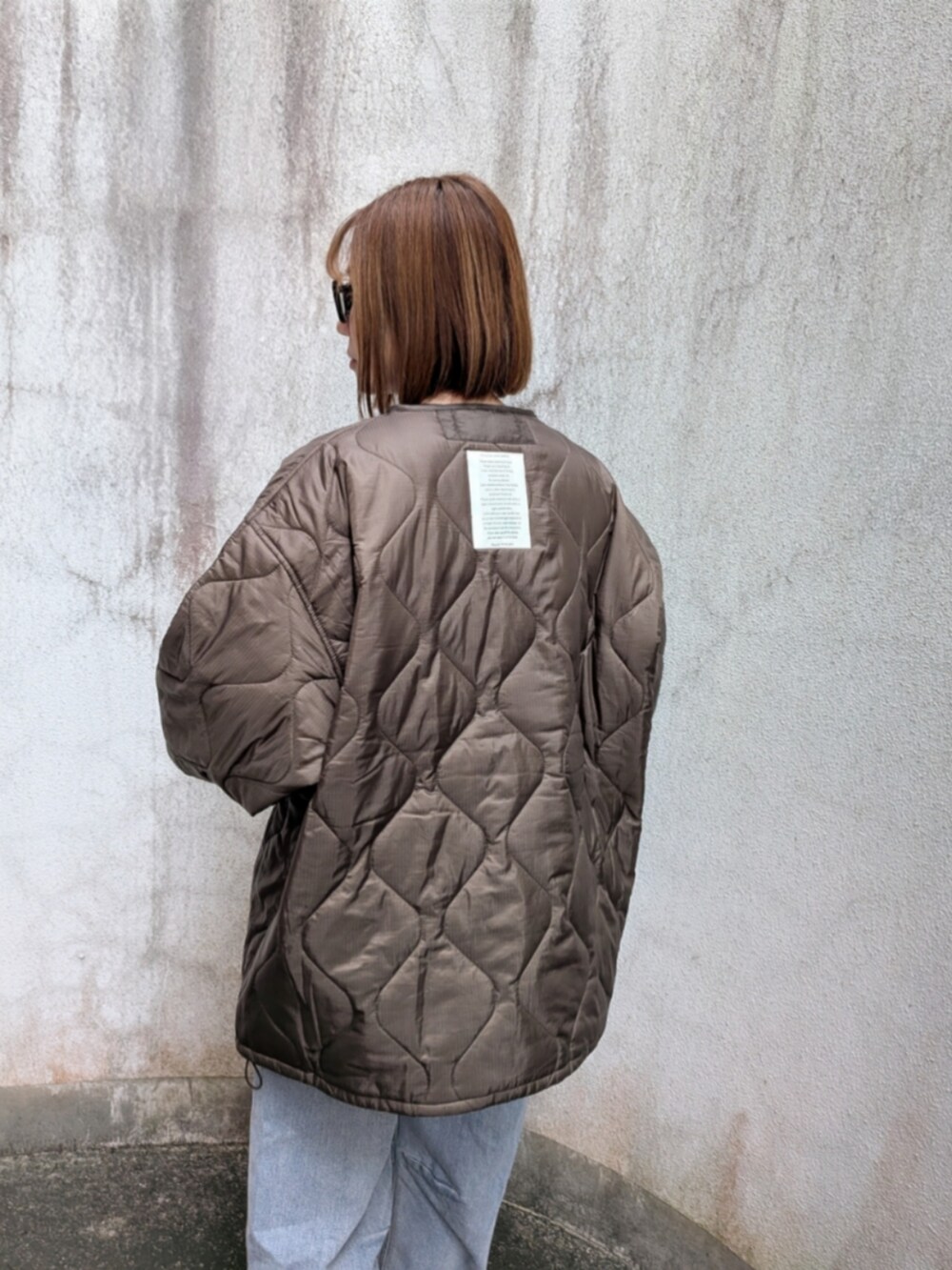 ブラウン系のブルゾン、ブルー系のデニムパンツ、ホワイト系のトートバッグを着用したレディースの秋コーディネートの4枚目の写真