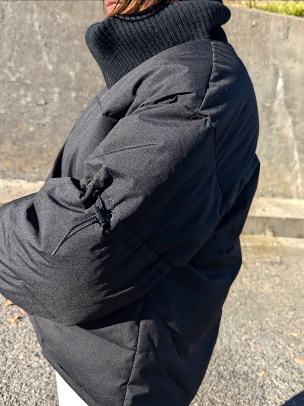 ブラック系のダウンジャケット/コート、ベージュ系のブーツ、ホワイト系のスカートを着用したレディースの冬コーディネートの4枚目の写真