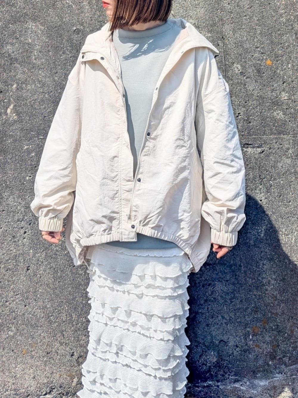 ホワイト系のナイロンジャケット、グリーン系のスウェット、ホワイト系のスカートを着用したレディースの春コーディネートの3枚目の写真