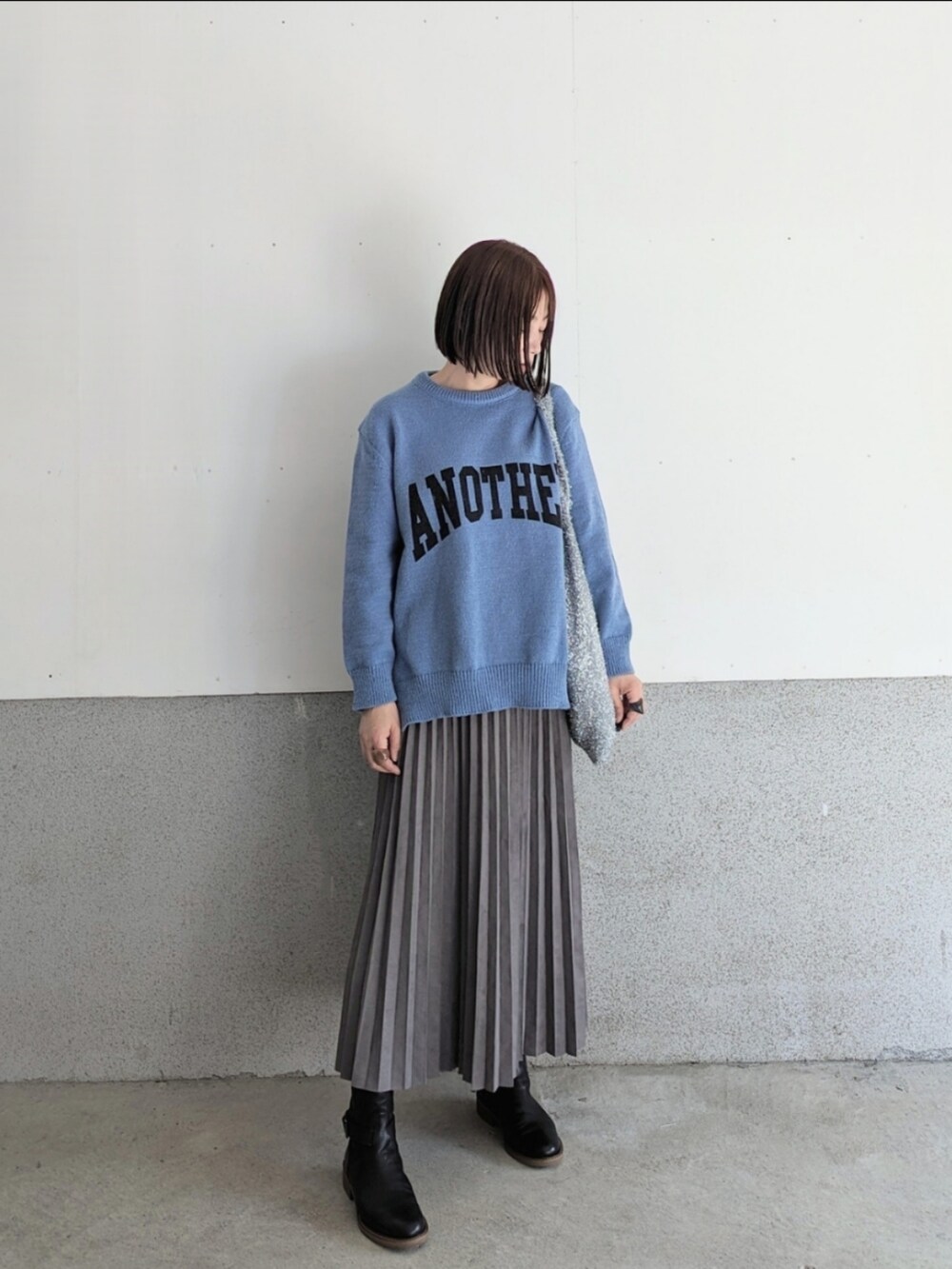 グレー系のスカート、ブラック系のブーツ、シルバー系のショルダーバッグを着用したレディースの秋コーディネートの4枚目の写真