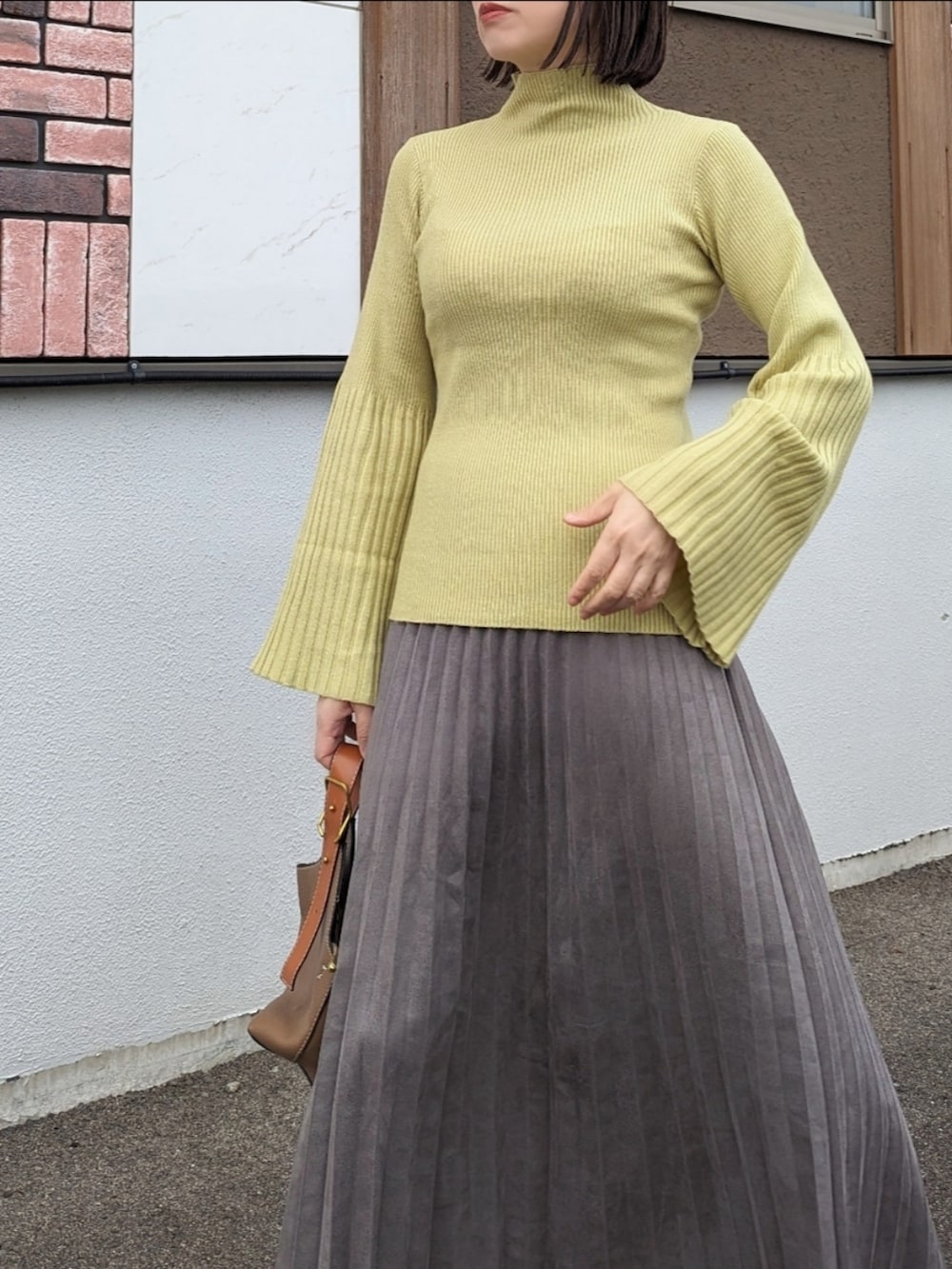 グリーン系のニット/セーター、グレー系のスカート、ベージュ系のブーツを着用したレディースの秋コーディネートの2枚目の写真