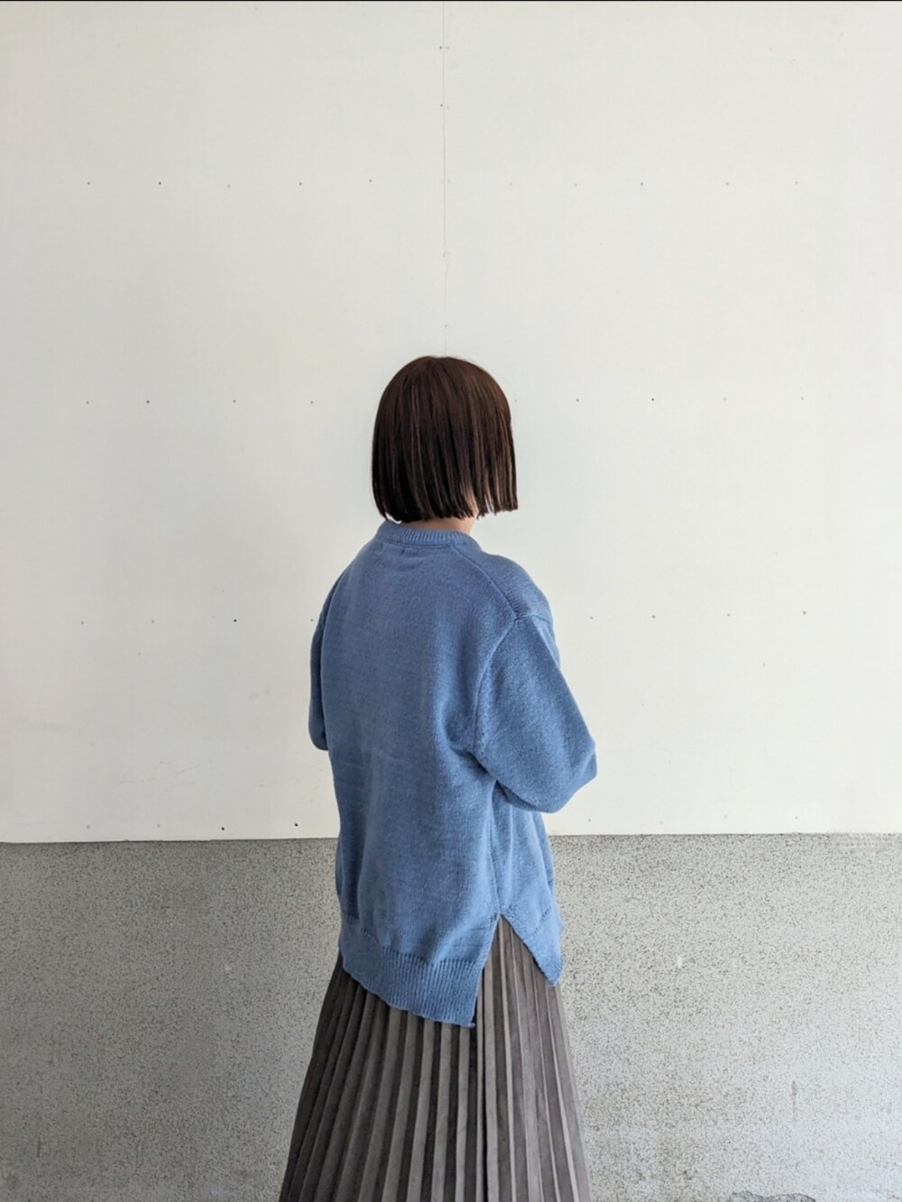 グレー系のスカート、ブラック系のブーツ、シルバー系のショルダーバッグを着用したレディースの秋コーディネートの3枚目の写真