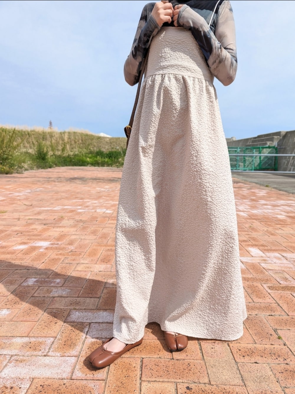 ベージュ系のワンピース、グリーン系のその他トップス、ブラウン系のパンプスを着用したレディースの春コーディネートの2枚目の写真