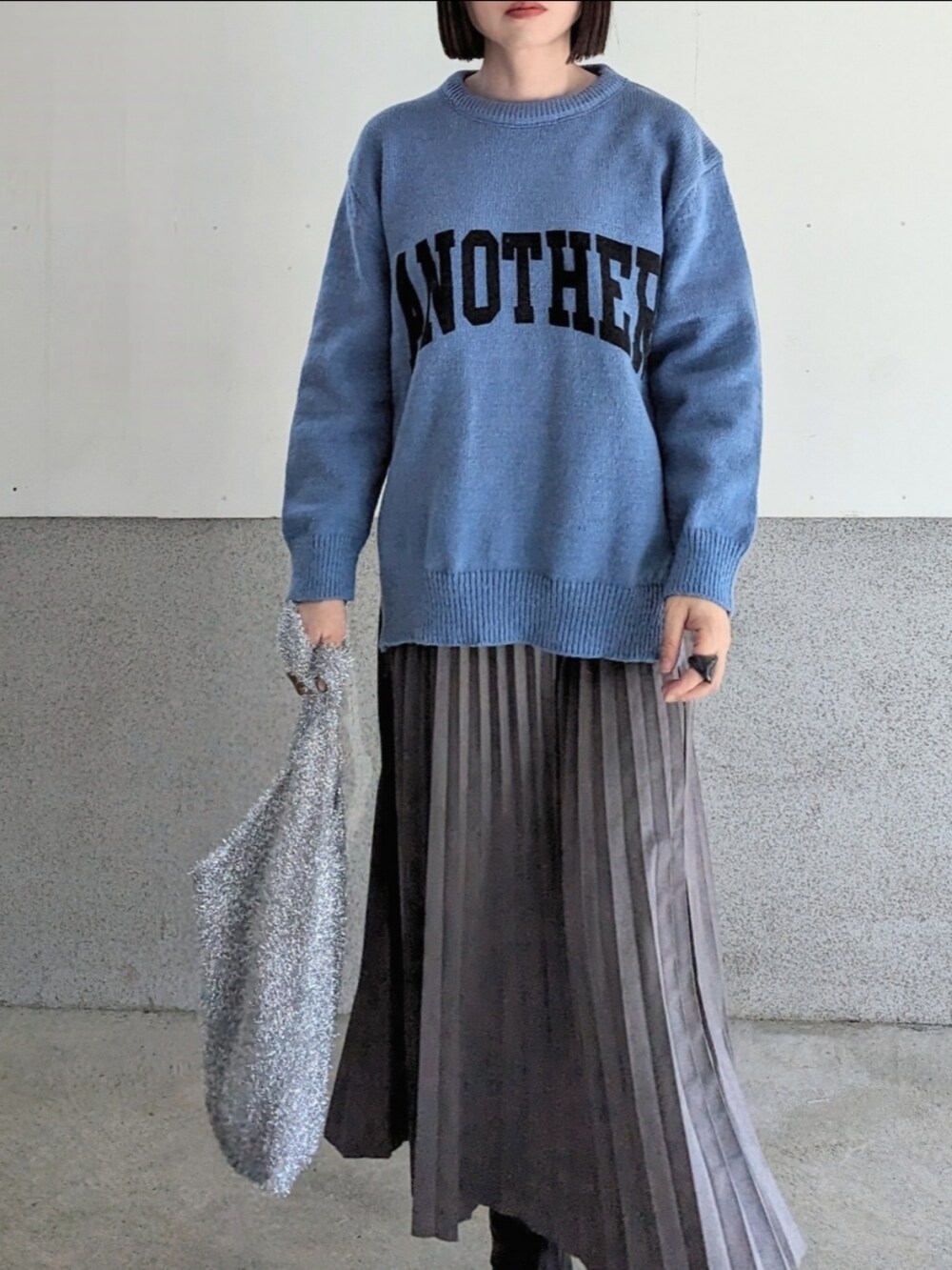 グレー系のスカート、ブラック系のブーツ、シルバー系のショルダーバッグを着用したレディースの秋コーディネートの2枚目の写真