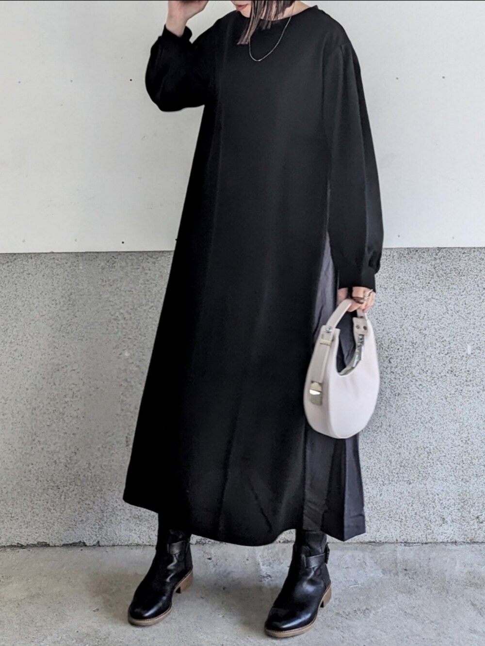 ブラック系のワンピース、ブラック系のブーツ、ホワイト系のハンドバッグを着用したレディースの秋コーディネートの2枚目の写真