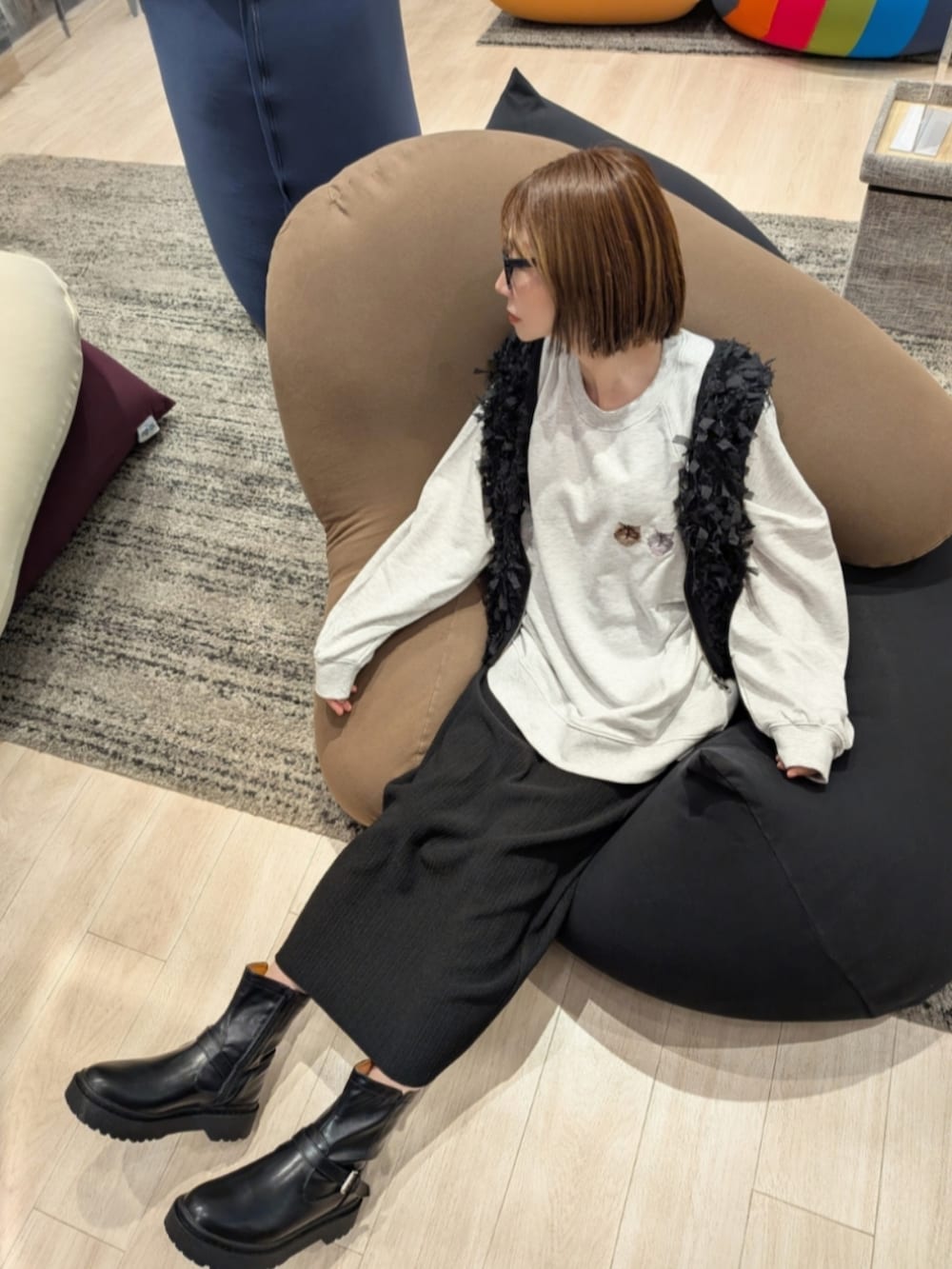 ベージュ系のスウェット、グレー系のトートバッグ、ブラック系のスカートを着用したレディースの秋コーディネートの2枚目の写真